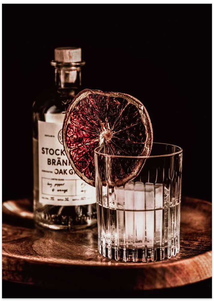 Cocktail dried orange poster with a photo of a cocktail glass with ice and a dried blood orange slice next to a bottle